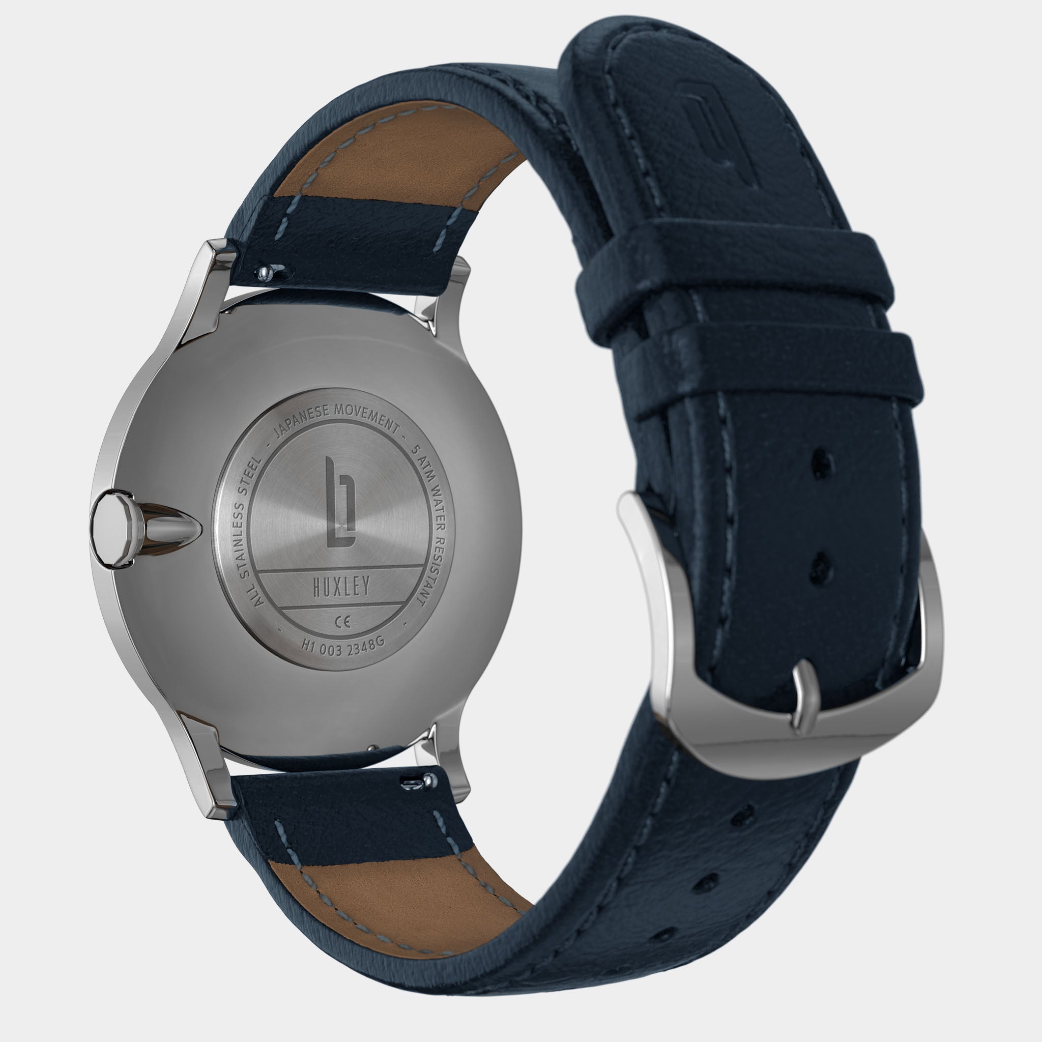 Stainless steel watch case back with blue leather strap, showcasing engraved details.