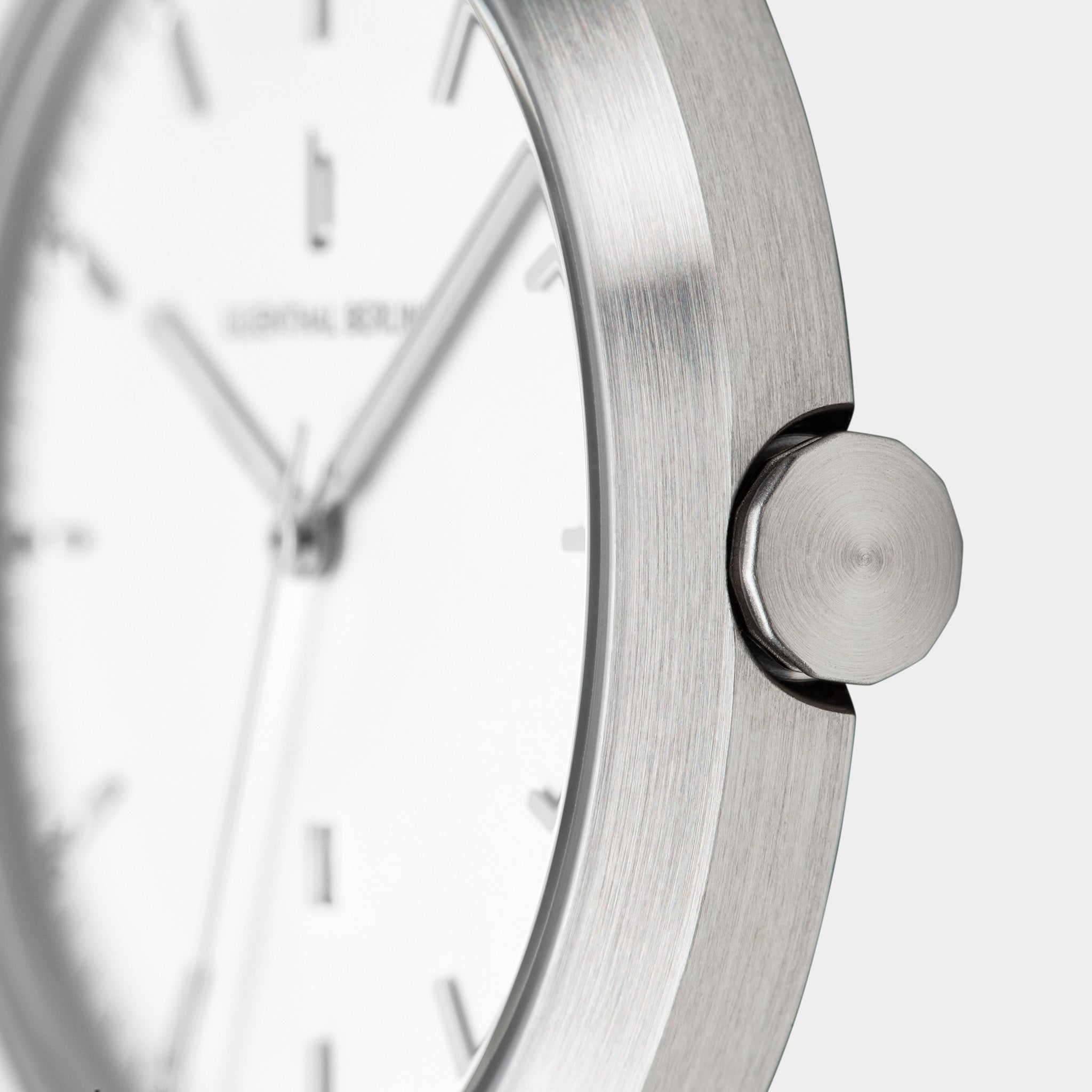 Close-up of minimalist silver wristwatch with brushed metal case and white dial