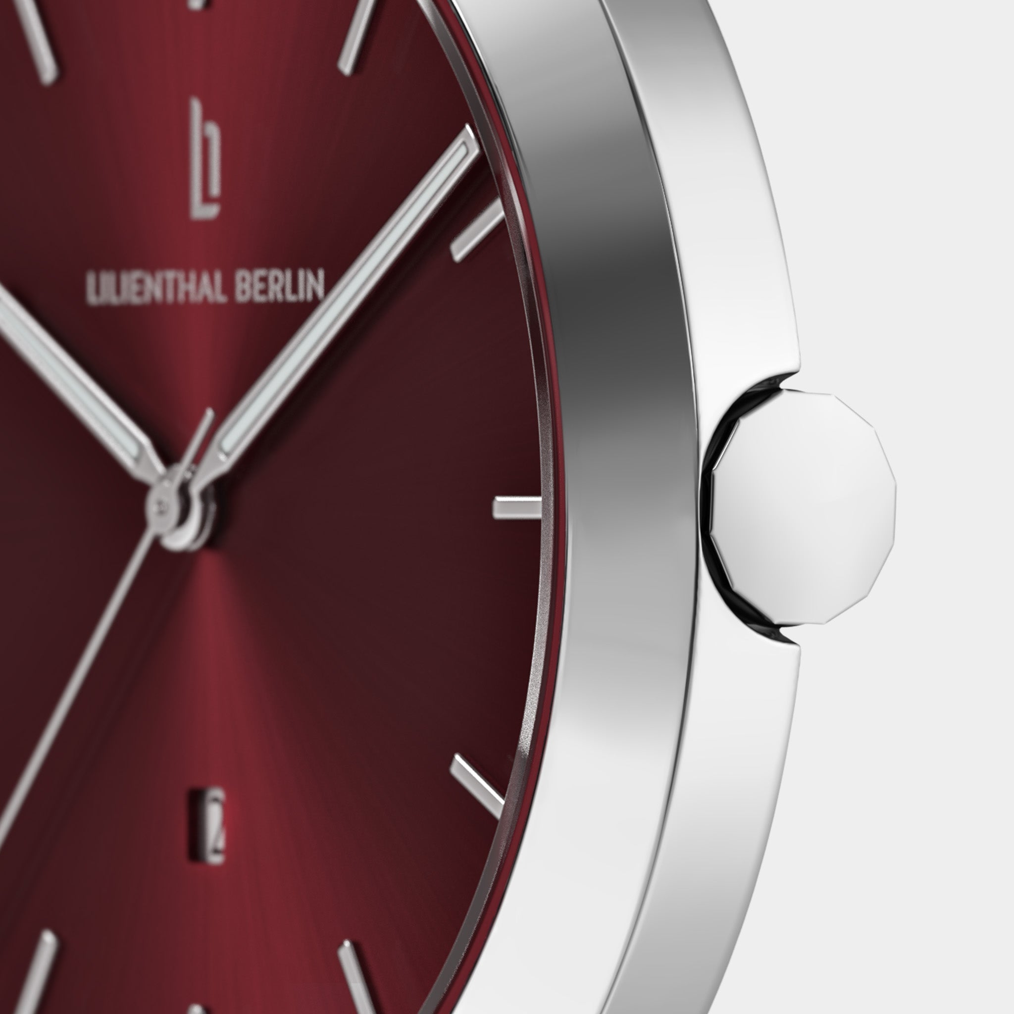 Close-up of a red minimalist watch face with silver markers, hands, and metallic case
