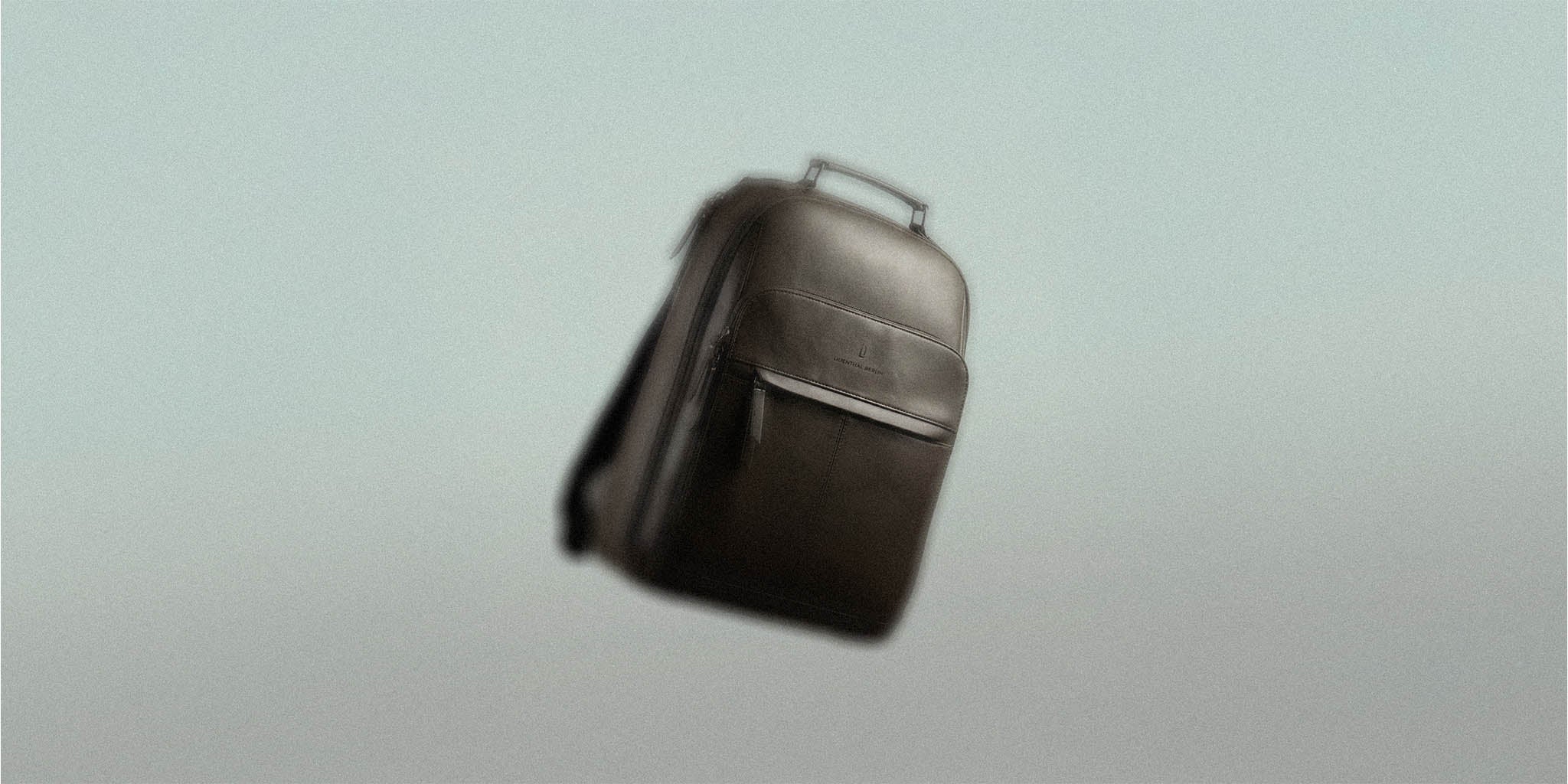 Sleek black backpack with top handle and front pocket on neutral background
