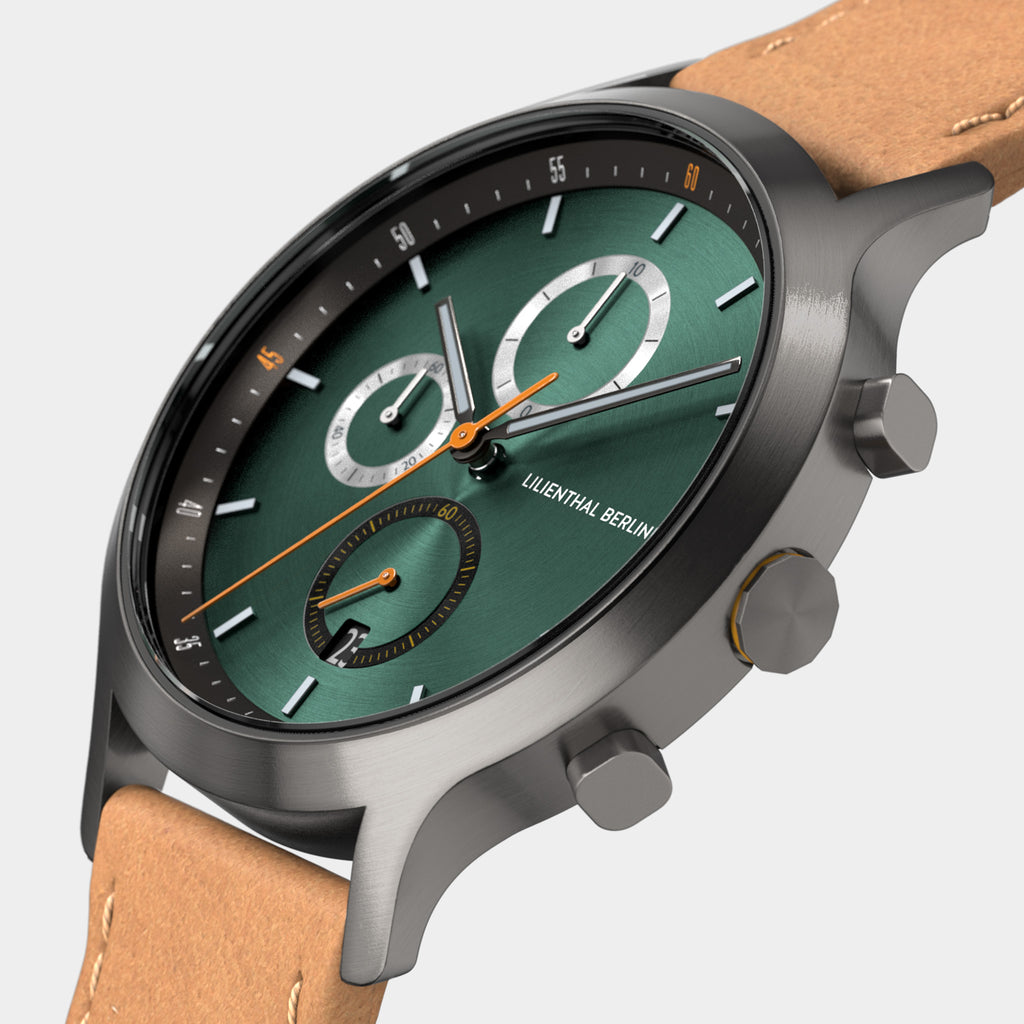 Green chronograph watch with brown leather strap and silver case on white background