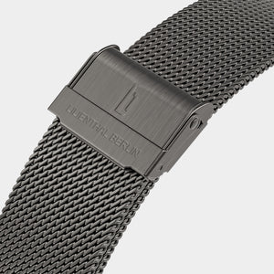 Close-up of a stainless steel mesh watch strap with clasp and engraved branding