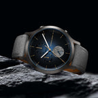 Elegant black wristwatch with gold details, blue dial, grey leather strap, date display