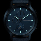 Modern black and blue chronograph watch with luminous hands and subdials on dark background