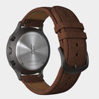 Close-up of chronograph watch case back with brown leather strap and stainless steel details