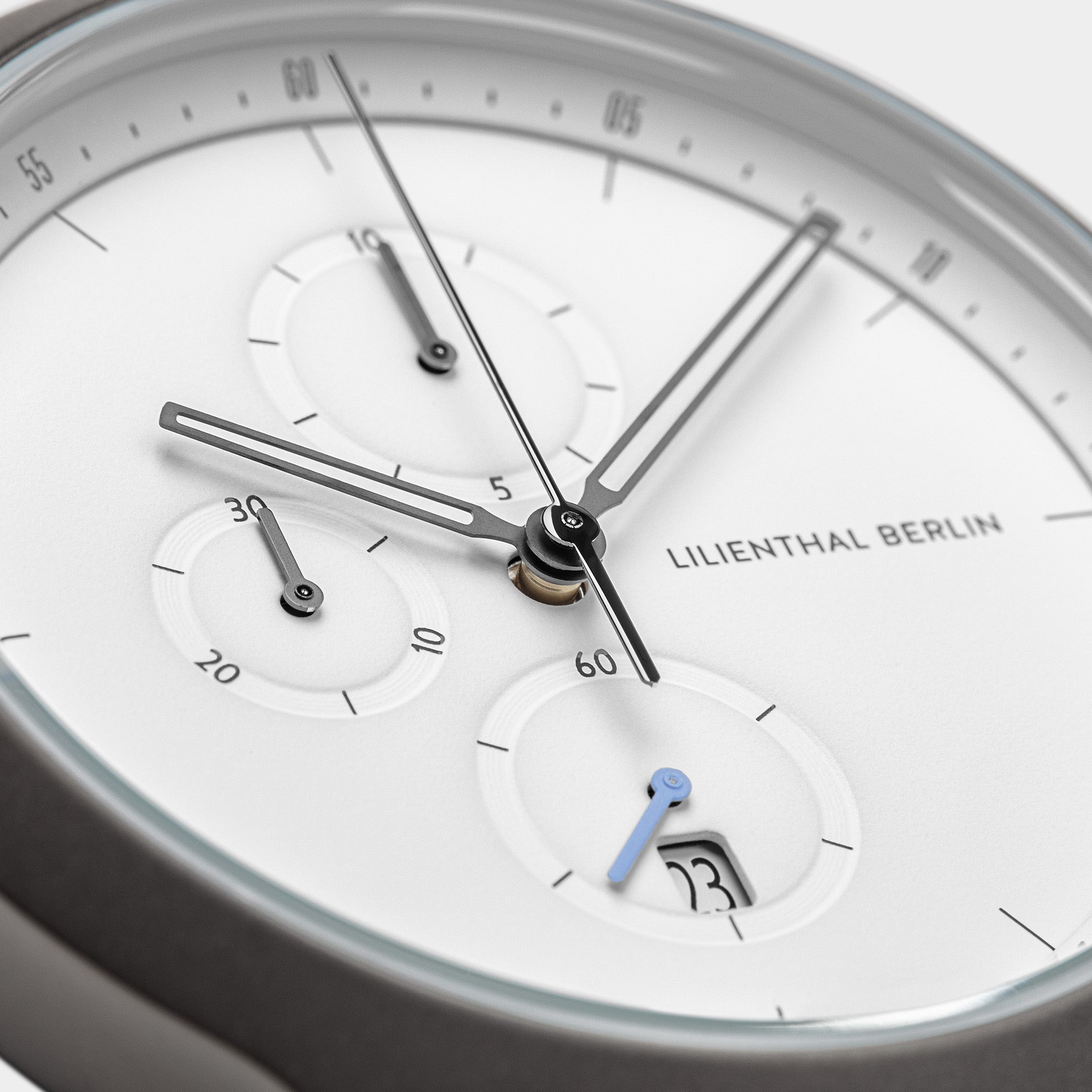 Minimalist white chronograph watch face with subdials and date display, close-up view