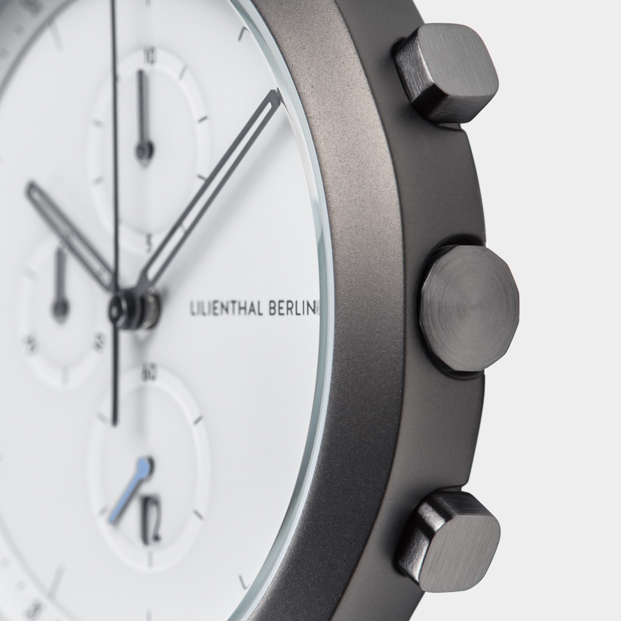 Close-up of a modern chronograph watch with white dial and brushed metal case