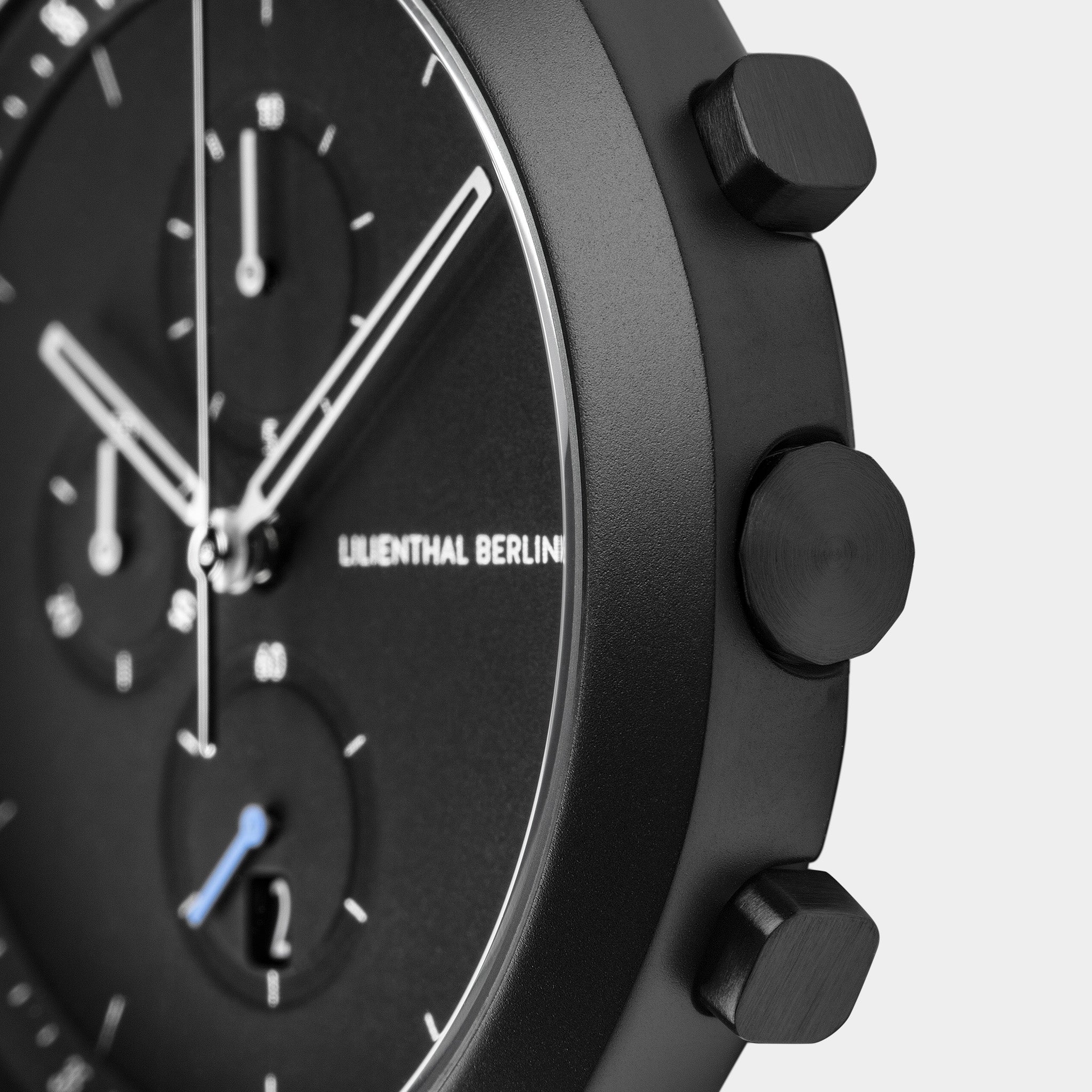 Close-up of black chronograph watch with subdials and side pushers on matte case
