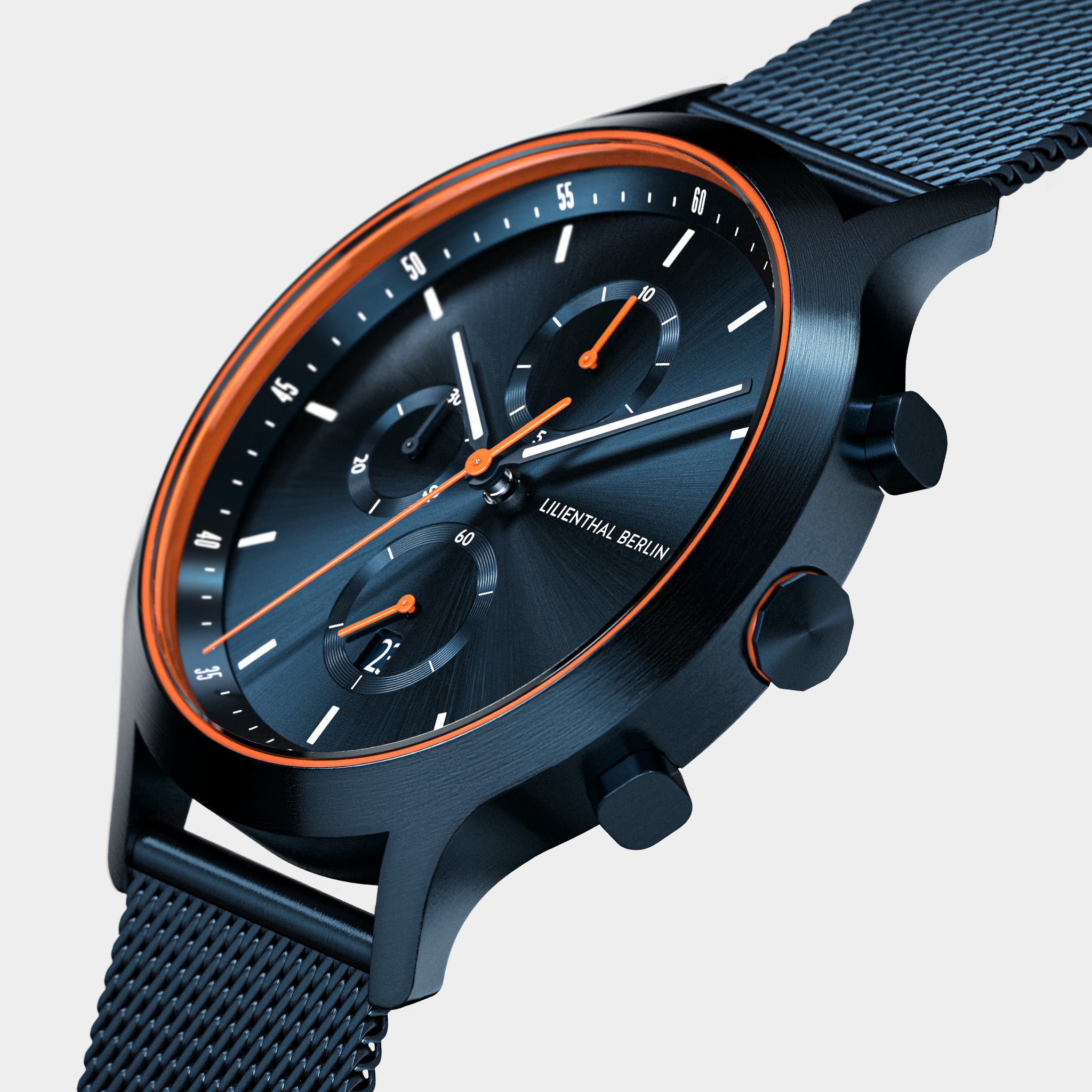 Black chronograph watch with orange accents, mesh strap, and subdials on a white background.