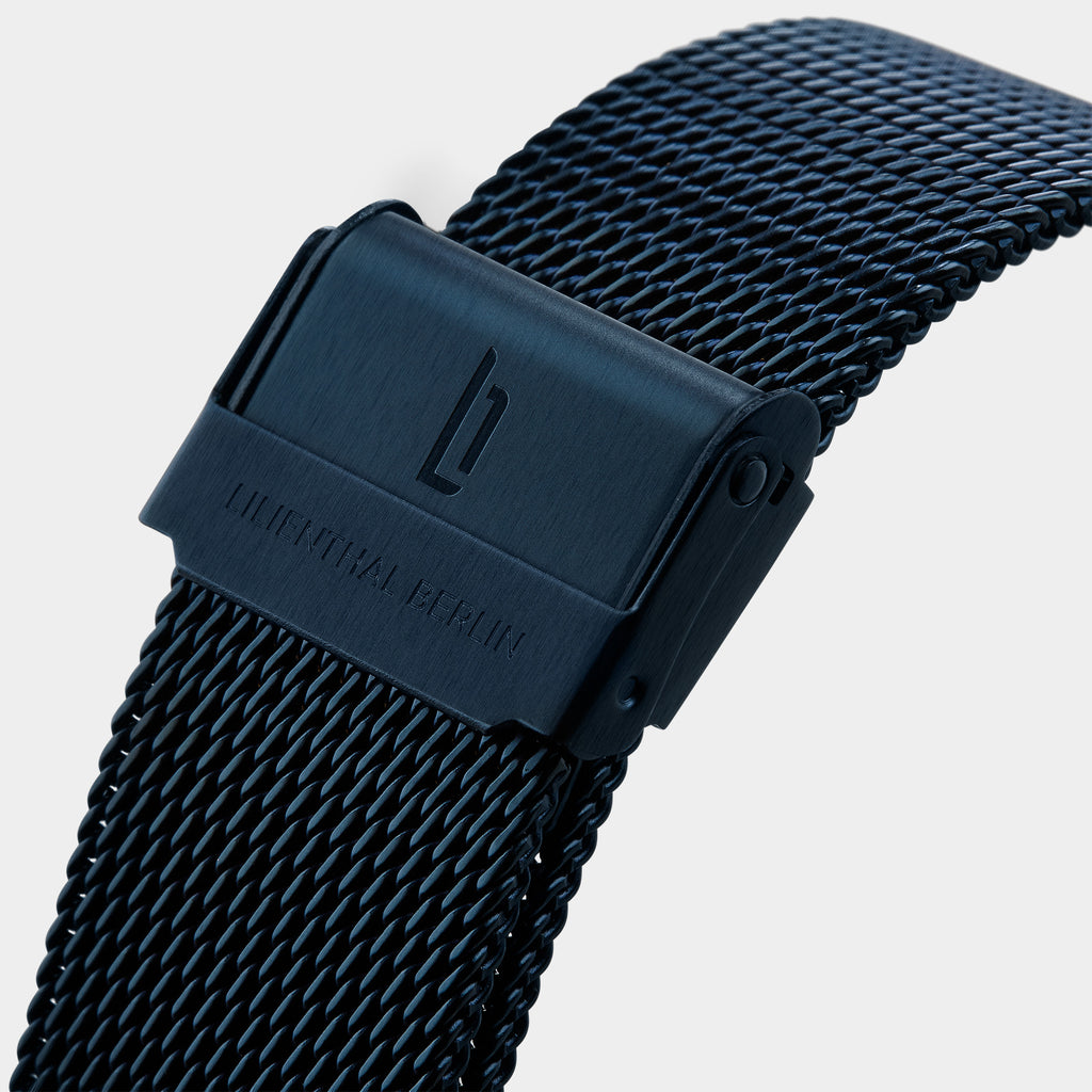 Black mesh stainless steel watch strap with engraved clasp on white background