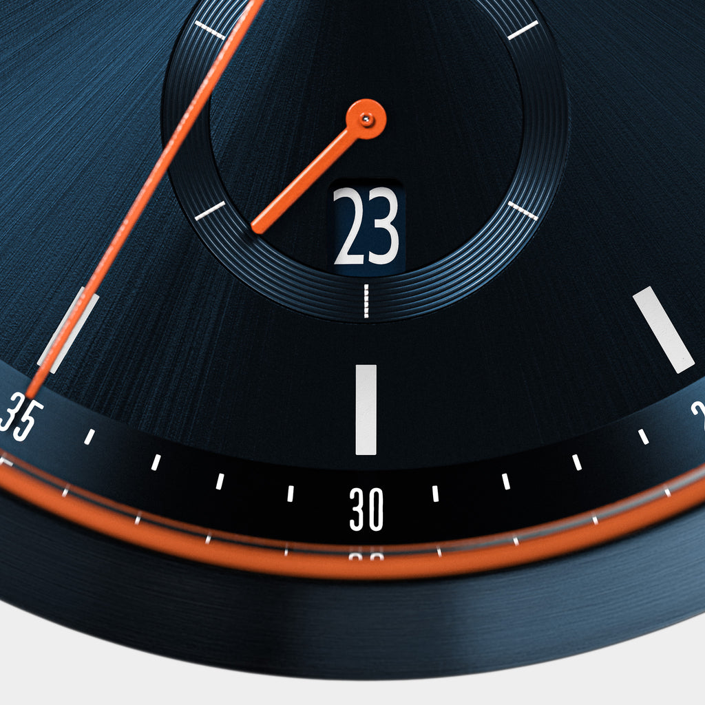 Close-up of a modern black watch face with orange hands, date display, and minimal hour markers