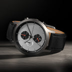 Luxury chronograph wristwatch with silver dial, black subdials, and black leather strap