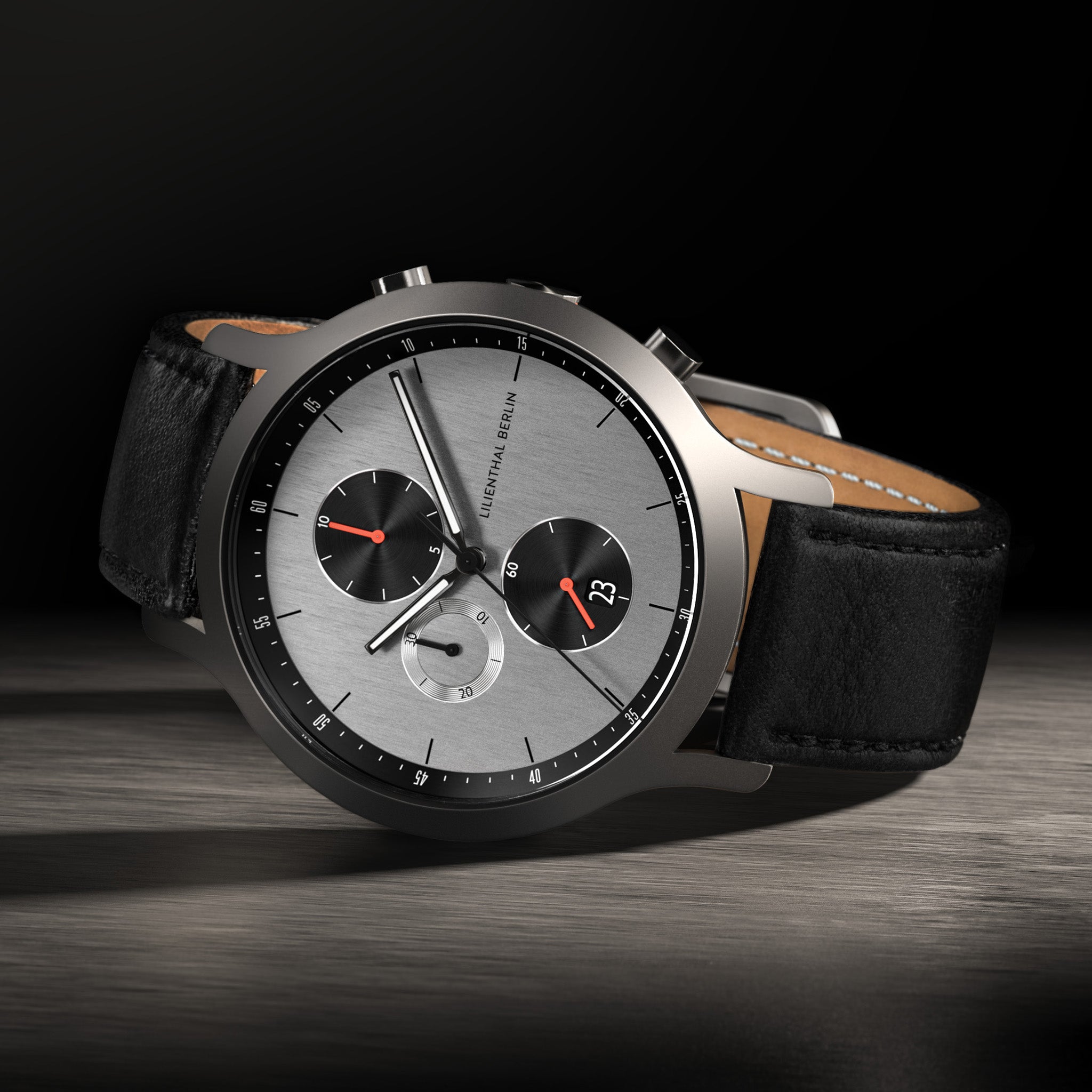 Luxury chronograph wristwatch with silver dial, black subdials, and black leather strap
