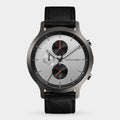 Silver chronograph watch with black leather strap, multi-dial face, and red accents