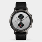 Silver chronograph watch with black leather strap, multi-dial face, and red accents