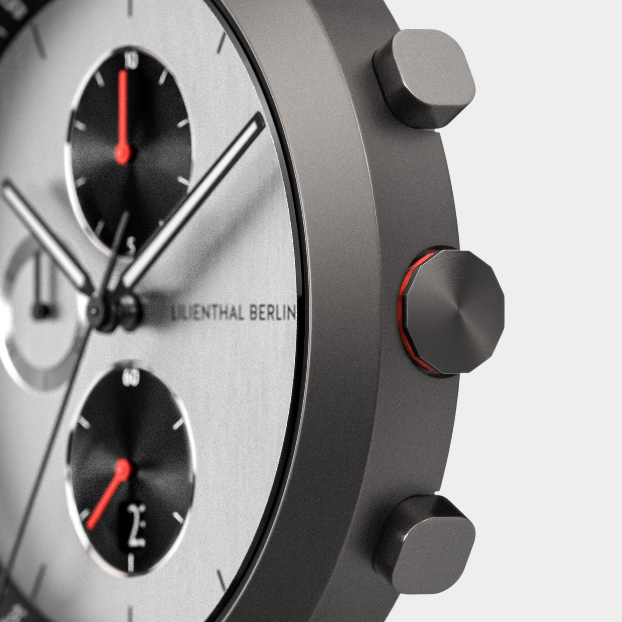 Close-up of a modern chronograph watch with metallic case, dual subdials, and red accents.
