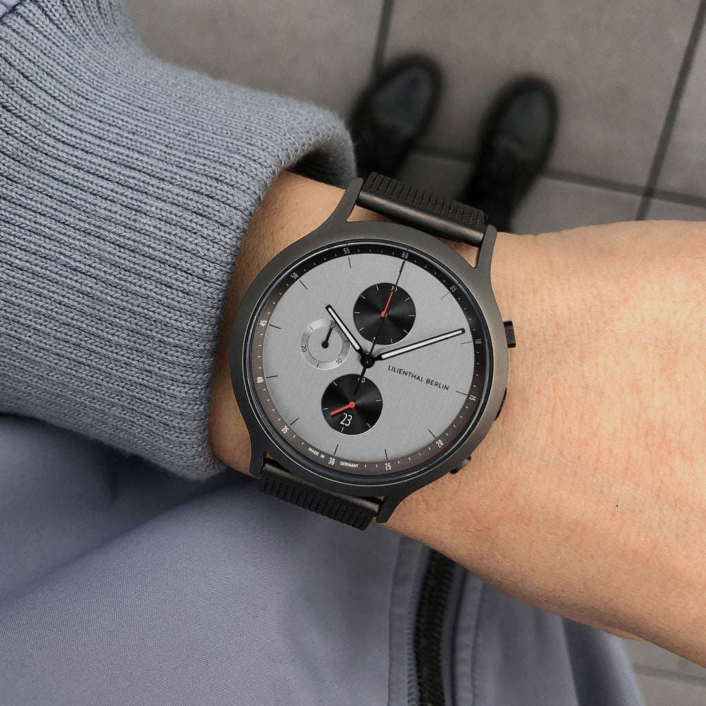 Minimalist black and grey chronograph watch with date display on a wrist, modern style.