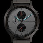 Modern chronograph watch with grey dial, black sub-dials, date window, and luminous hands