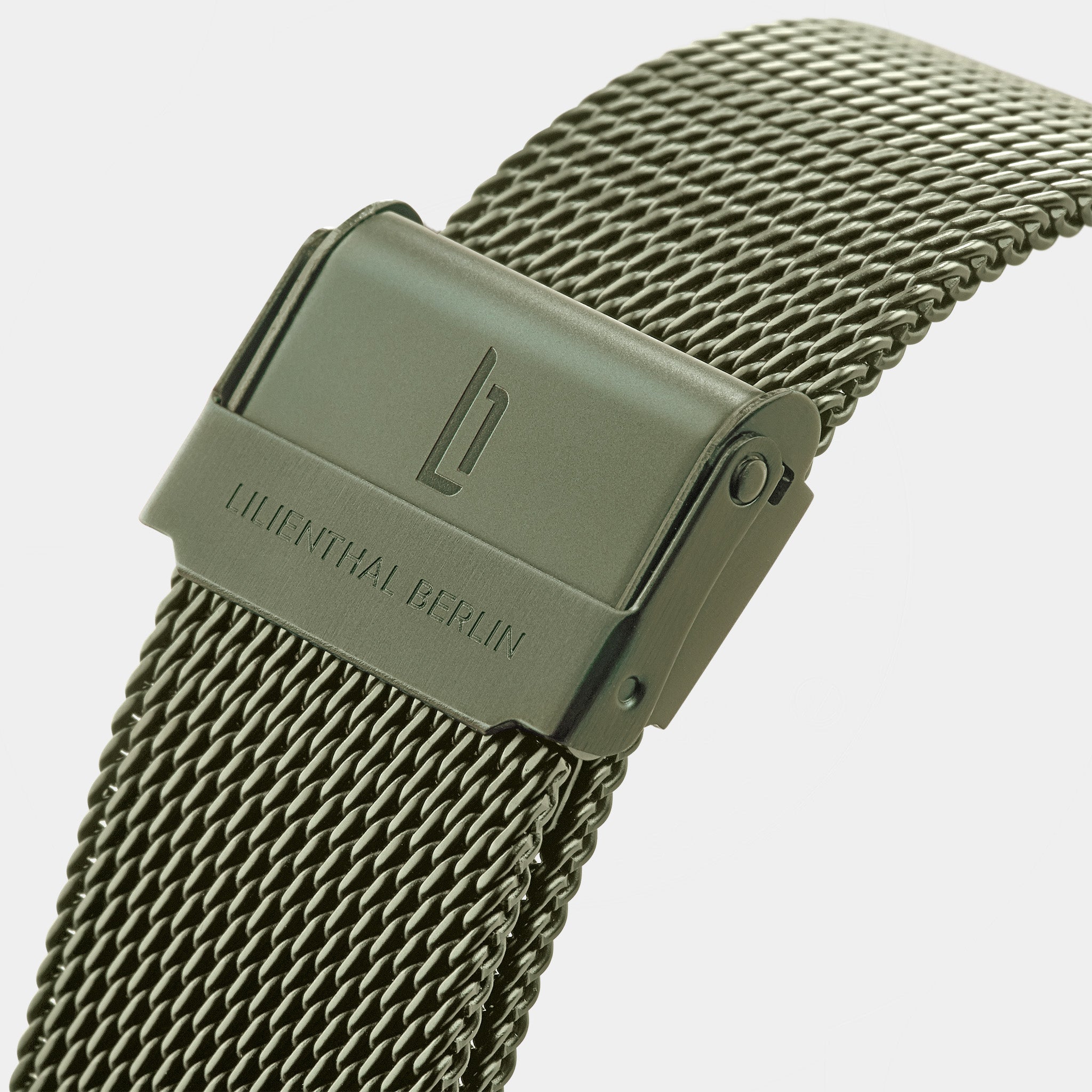 Close-up of green mesh stainless steel watch strap with clasp and engraved text