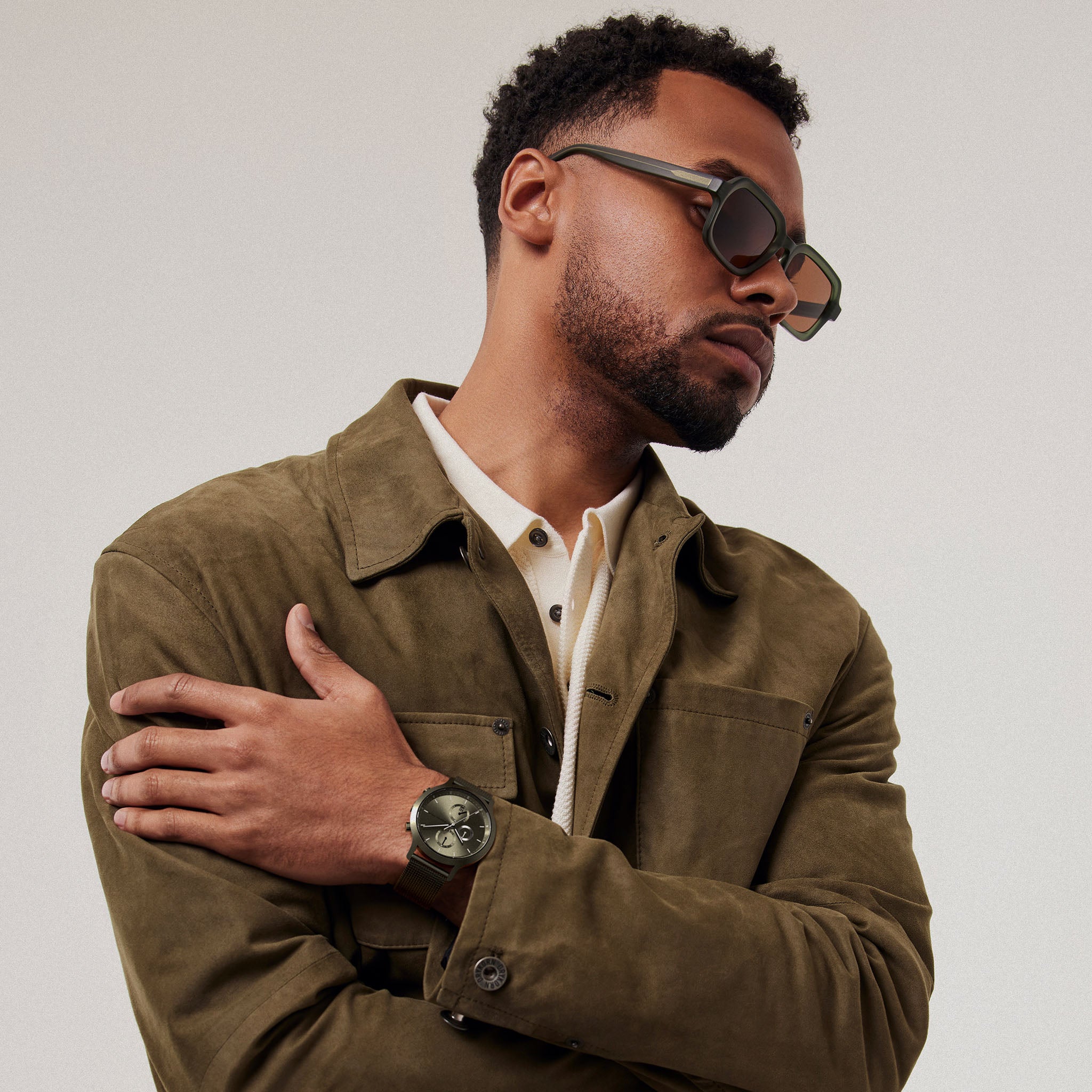 Man wearing stylish square sunglasses and modern wristwatch with olive green jacket