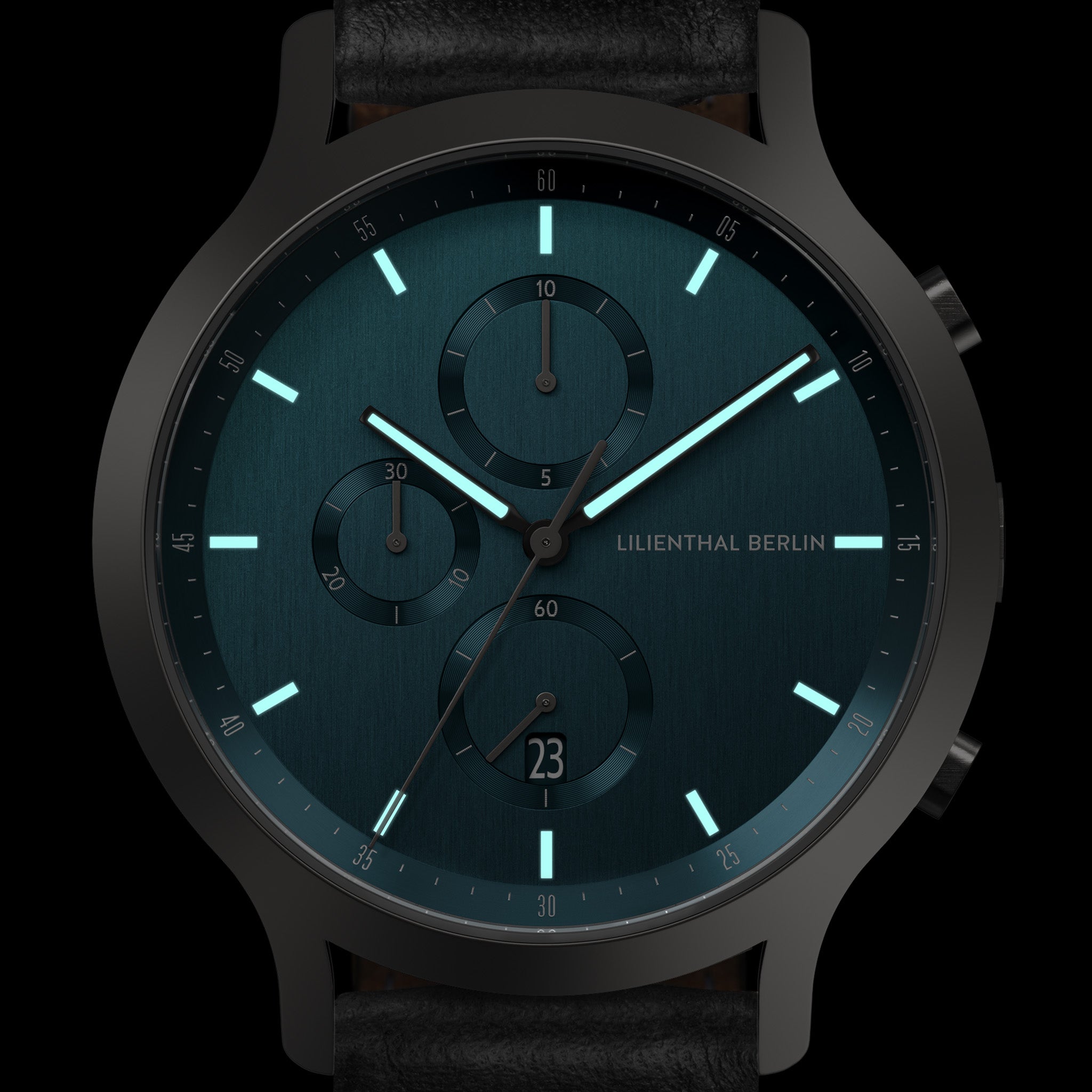 Modern dark teal chronograph watch with subdials, date display, luminous hands, black strap