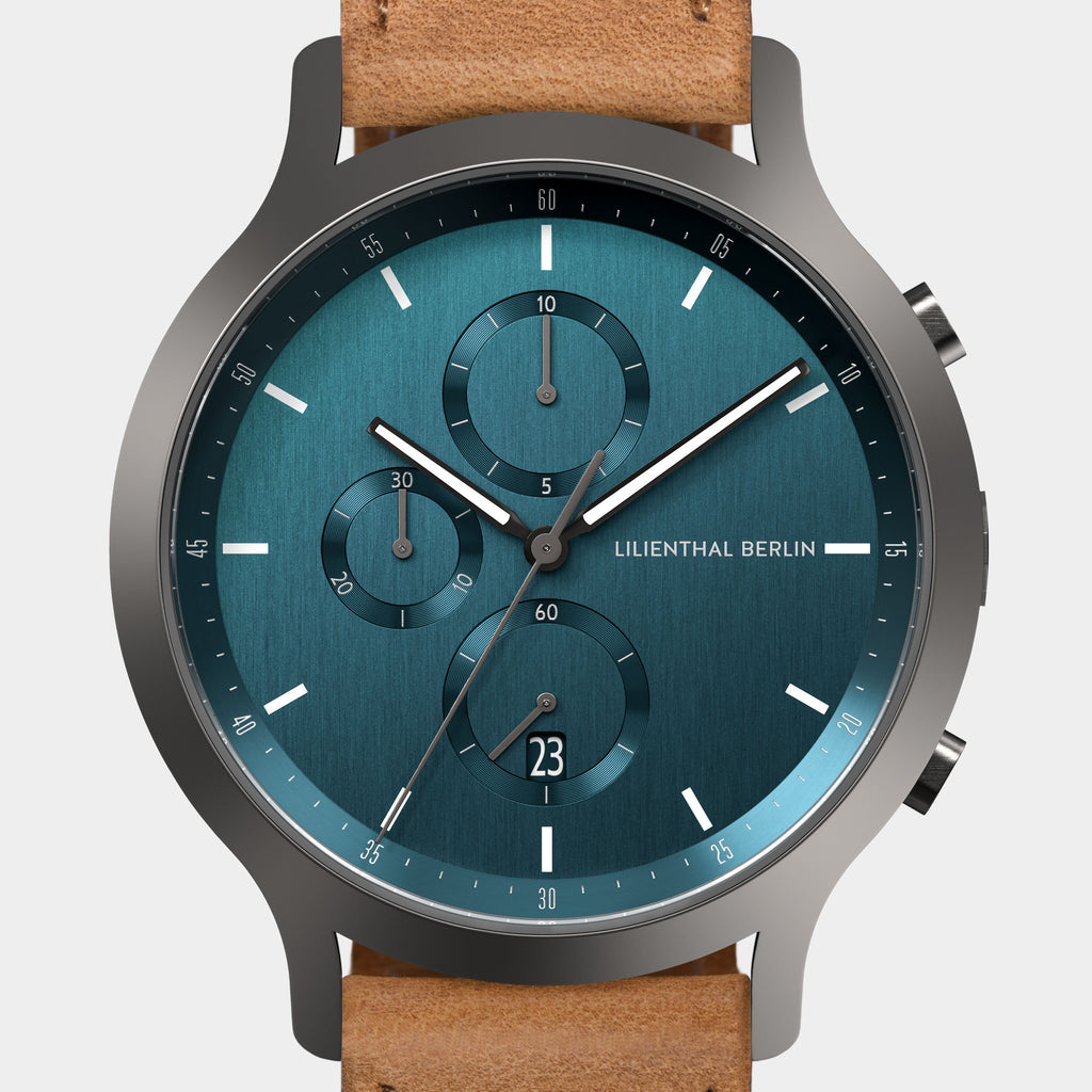 Modern chronograph watch with blue dial, subdials, date display, and tan leather strap