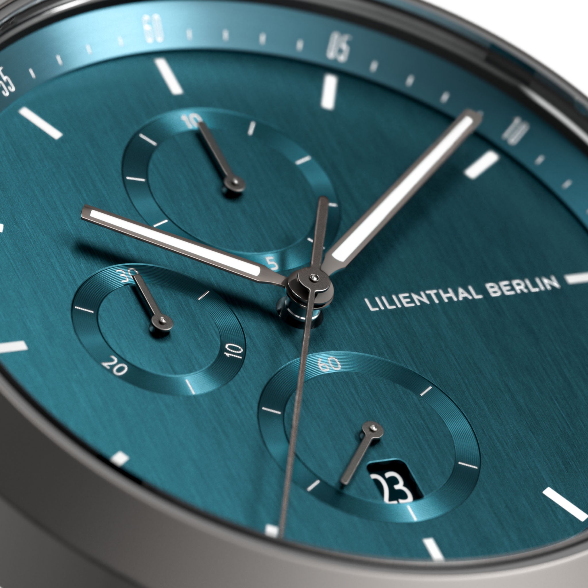 Close-up of teal chronograph watch face with subdials, date display, and silver hands