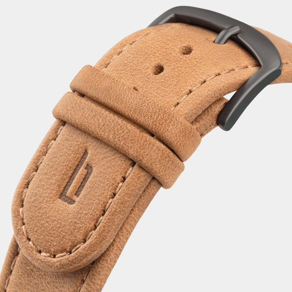 Close-up of tan leather watch strap with stitched edges and matte black buckle