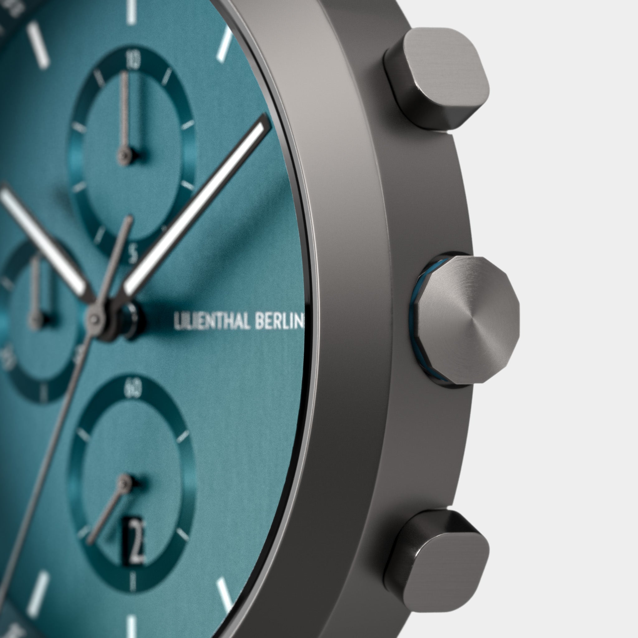 Close-up of a modern teal chronograph watch face with metallic case and push buttons