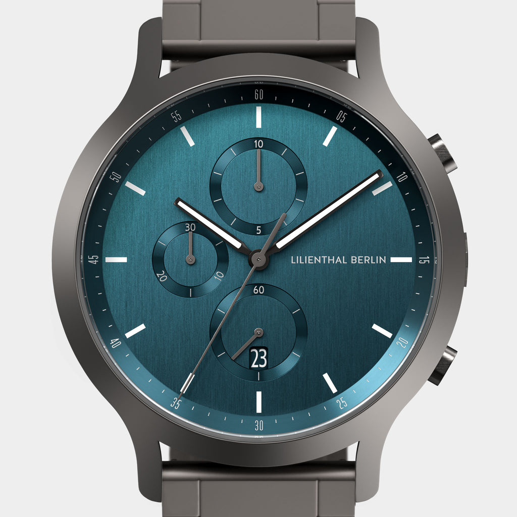 Modern chronograph wristwatch with blue textured face, three subdials, and metal strap
