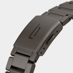 Close-up of brushed metal watch bracelet clasp with engraved logo, modern design