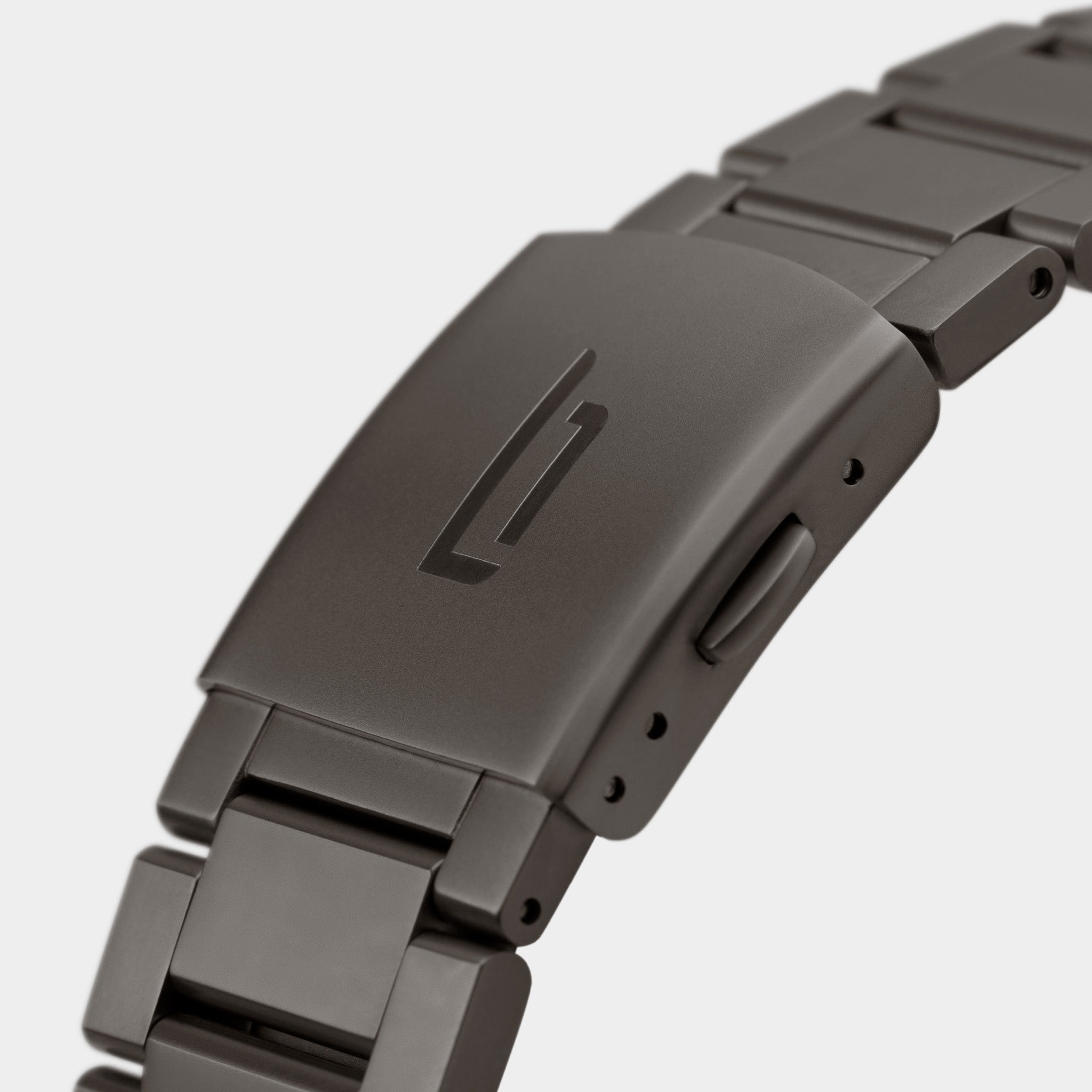 Close-up of brushed metal watch bracelet clasp with engraved logo, modern design