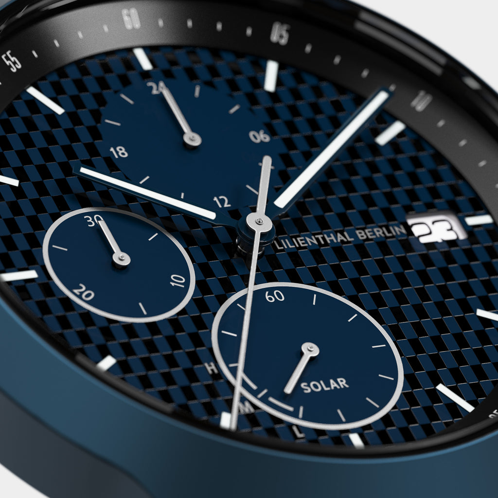 Close-up of a blue solar chronograph watch with subdials and date display.