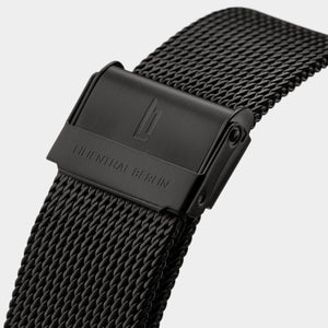 Black stainless steel mesh watch strap with engraved clasp, close-up view