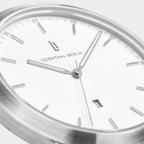 Minimalist silver analog wristwatch with white dial and date display, close-up view