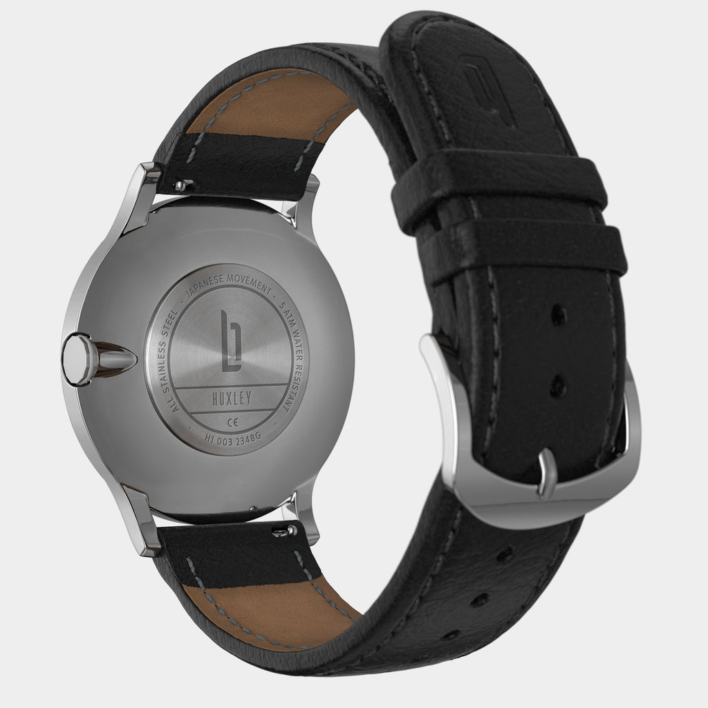 Back view of stainless steel watch with black leather strap and engraved case details