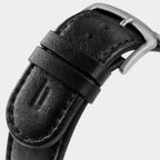 Close-up of black leather watch strap with stainless steel buckle