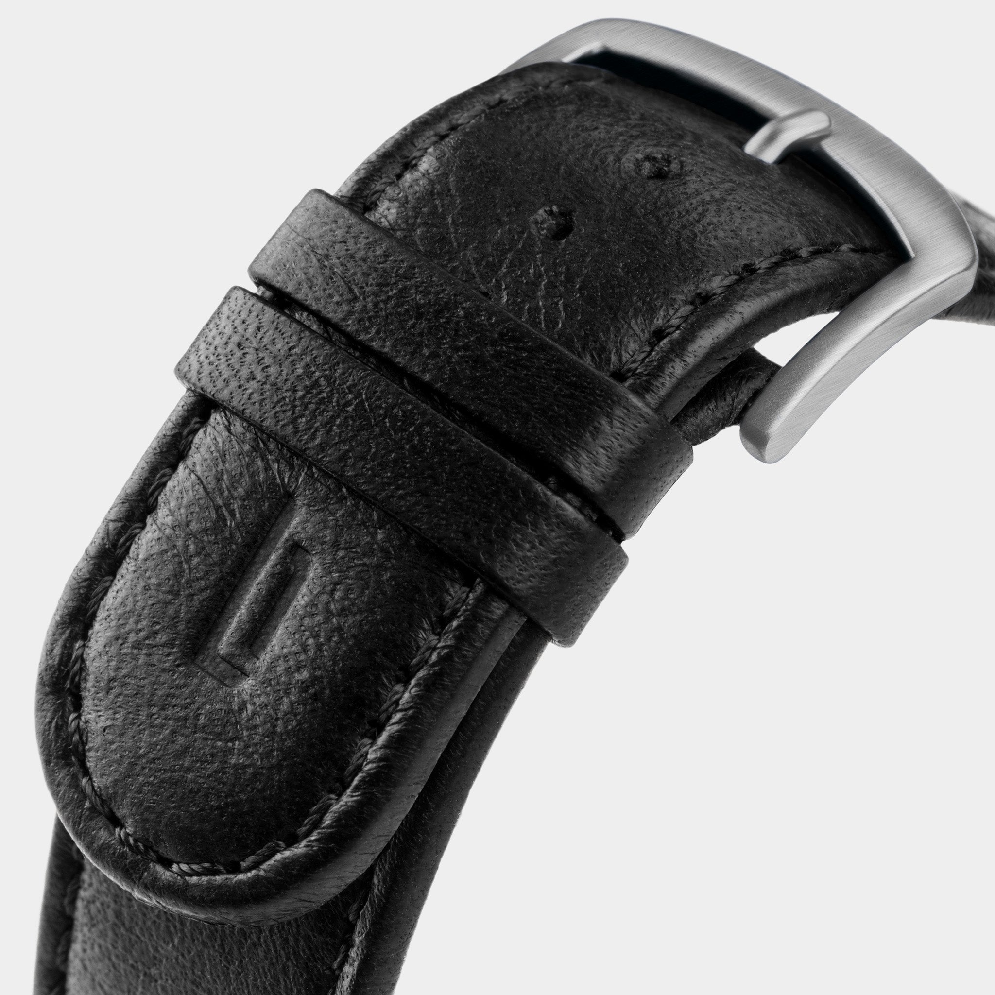 Close-up of black leather watch strap with stainless steel buckle