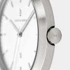 Close-up of minimalist silver wristwatch with brushed metal case and white dial