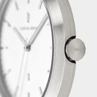 Minimalist silver watch close-up with brushed metal case and white dial