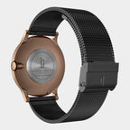 Back view of a rose gold watch case with stainless steel mesh black strap and engraved details