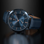 Elegant black wristwatch with rose gold markers and dark leather strap on a reflective surface