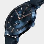 Close-up of a blue minimalist wristwatch with rose gold markers and a leather strap