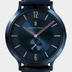 Minimalist blue wristwatch with rose gold hands and numerals, black leather strap