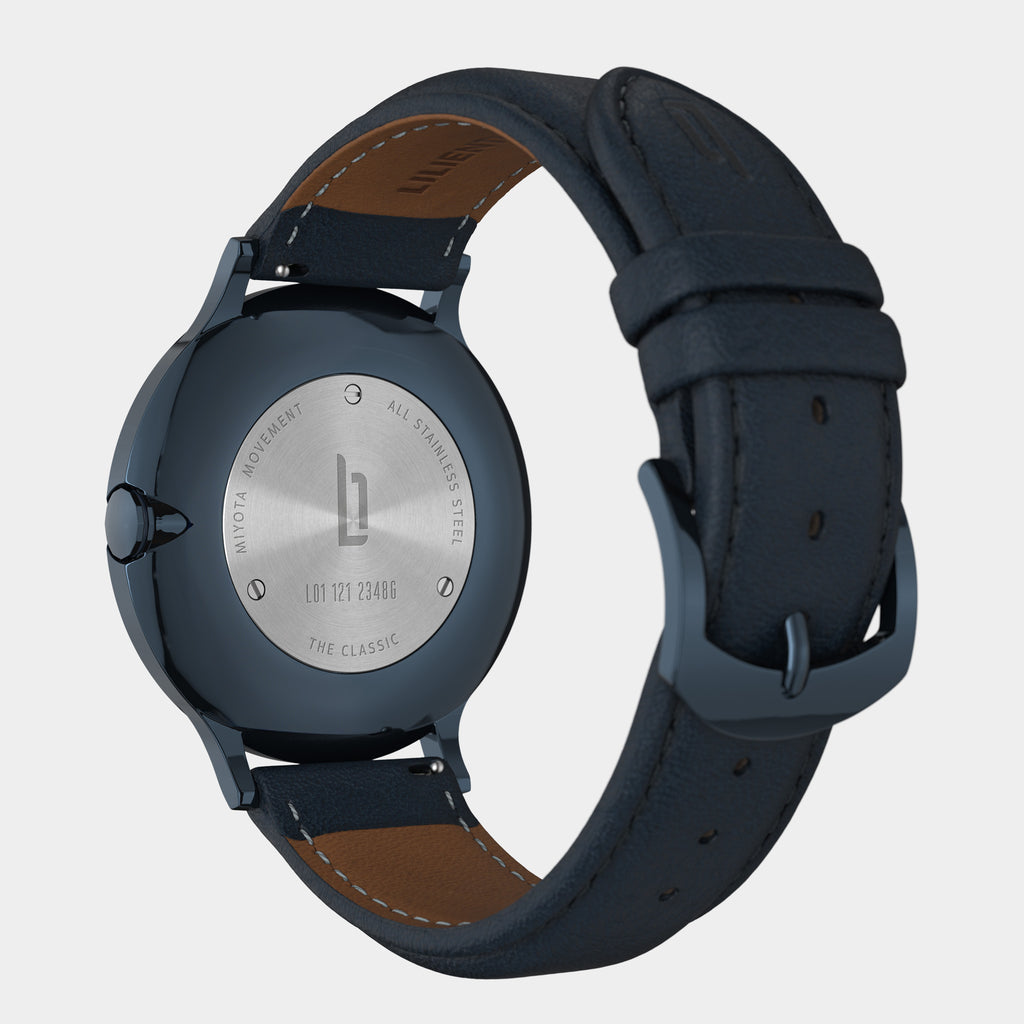 Close-up of a watch back with stainless steel case and navy leather strap