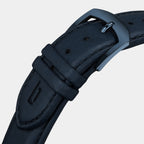 Close-up of navy leather watch strap with steel buckle and stitched detail