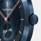 Close-up of minimalist blue watch with rose gold hands and hour markers on brushed dial